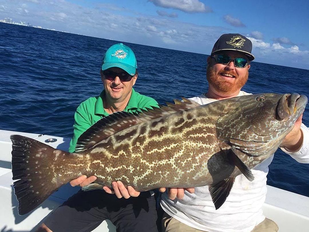 Two anglers with a large black grouper caught aboard Spellbound, Miami